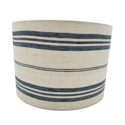 Cylindrical woven basket with blue stripes on a white background